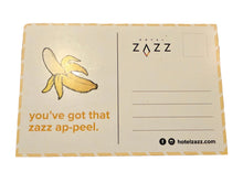 A rectangular postcard from Hotel Zazz. The postcard has a cream background with a yellow banana illustration on the left, orange text reading 'you've got that zazz ap-peel.