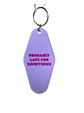 A lavender purple keychain with the text 'PROBABLY LATE FOR SOMETHING' in pink.