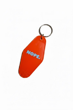 An orange plastic keychain tag with the word 'NOPE.' printed in blue, attached to a metal key ring.