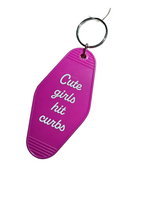 A bright pink keychain shaped like a shoe sole with the phrase 'Cute girls hit curbs' printed in white script, attached to a silver metal key ring.
